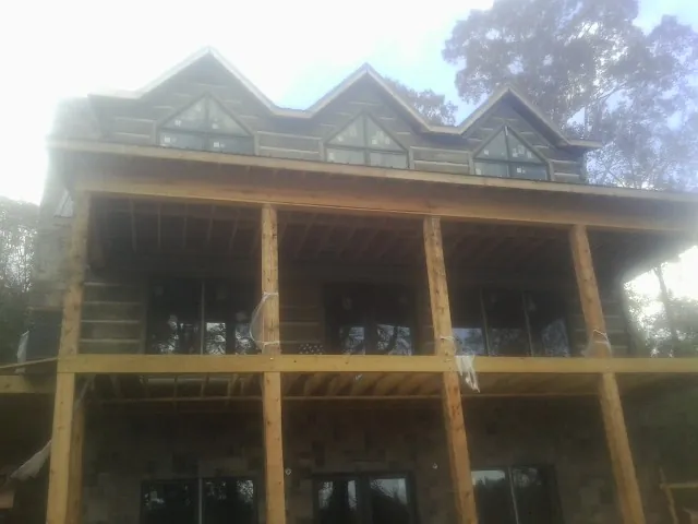 Dormers and porch framing on a large log home under construction — Roof Coating work by our crew in Delta